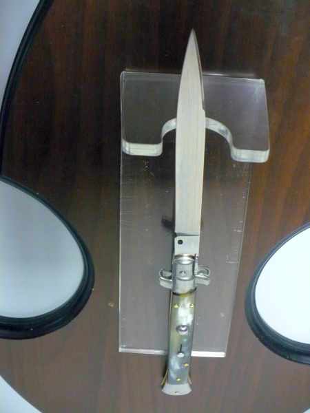 Italian stiletto with a polished steel blade and narrow silver-toned handle with small brass-colored details